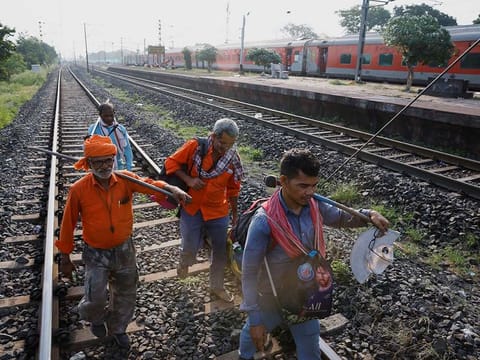 Workers walk on a rail track as a train arrives at Bahanaga Bazar railway station, near the site of a train collision following the accident in Balasore district in the eastern state of Odisha, India, June 5, 2023. 