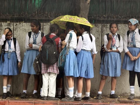 Children waiting for school bus under umbrellas in New Delhi, India 