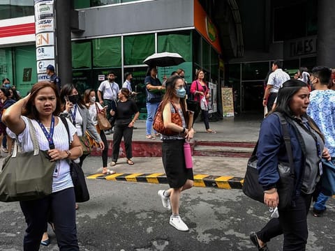 People gather on a street after evacuating a building in Manila on June 15, 2023, following a magnitude 6.3 earthquake struck the Philippines. 