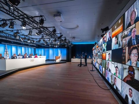International Olympic Committee members appear on a giant screen in Lausanne on Thursday, during an extraordinary hybrid IOC Session to vote to withdraw its recognition of the IBA.