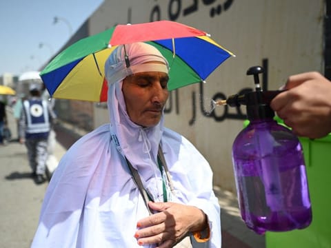 A member of the Saudi security forces sprays water on Muslim pilgrims during the Hajj pilgrimage in Mina, near Saudi Arabia's holy city of Mecca on June 29, 2023. 