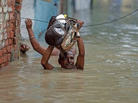 Residents move towards a safer place as the water level of the Yamuna river rose to a record level in the Yamuna Bazar area of New Delhi on Wednesday.  