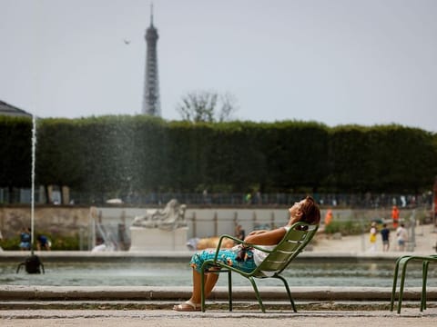 A woman enjoys the sun in the Tuileries gardens in Paris.