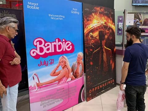 Moviegoers look at posters of 'Barbie' and 'Oppenheimer' at a cineplex on July 21, 2023. 