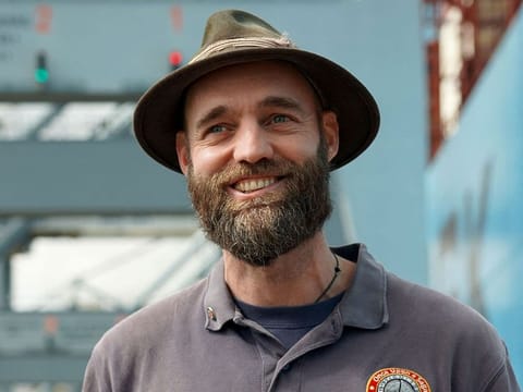 Torbjørn (Thor) Pedersen stands on the dock at the Port of Aarhus in Aarhus, Denmark on July 26, 2023, and smiles as he stepped off a large Maersk container ship, after visiting his 203rd country and final country -- the Maldives -- in late May 2023. 