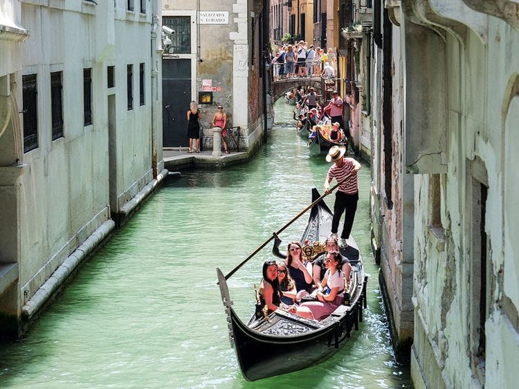 Gondoliers row their gondolas through the Venice Canal. 