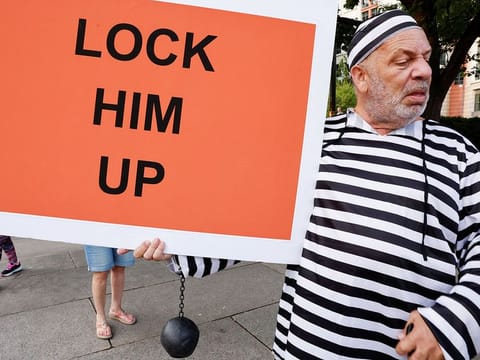 A man holds a sign in front of the E. Barrett Prettyman Federal Courthouse ahead of Donald Trump's arraignment in Washington, on August 2, 2023. 