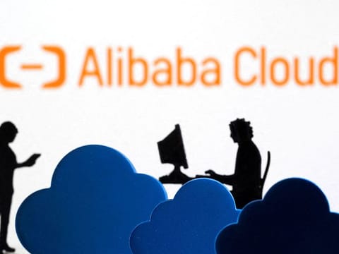 3D printed clouds and figurines are seen in front of the Alibaba Cloud service logo in this illustration. 