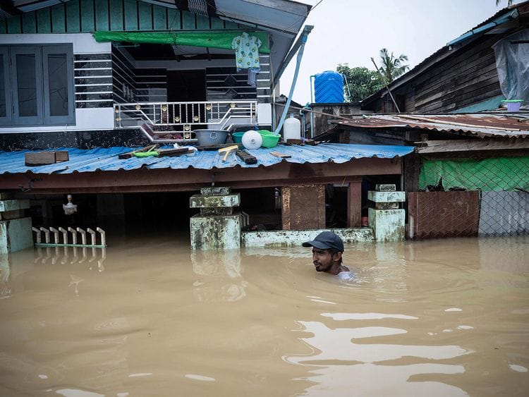 A man wades through a flooded street in Bago township in Myanmar's Bago region