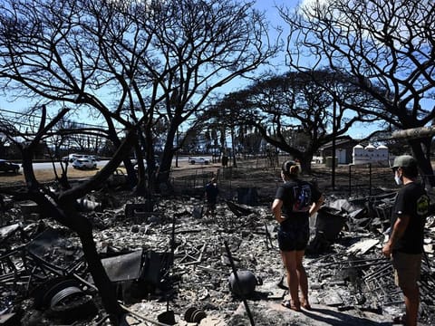Hano Ganer (Rear, C) and Taylor Ganer (Center Right) look through the ashes of their family’s home in the aftermath of a wildfire in Lahaina, western Maui, Hawaii on August 11, 2023