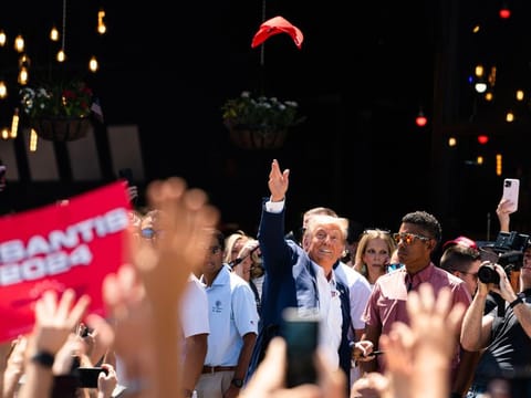 Former president Donald Trump tosses a hat in the air while supporters cheer for him on August  12, 2023, during the 2023 Iowa State Fair, in Des Moines.  