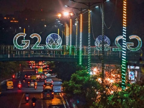Vehicles drive past G20 signage above a road in New Delhi