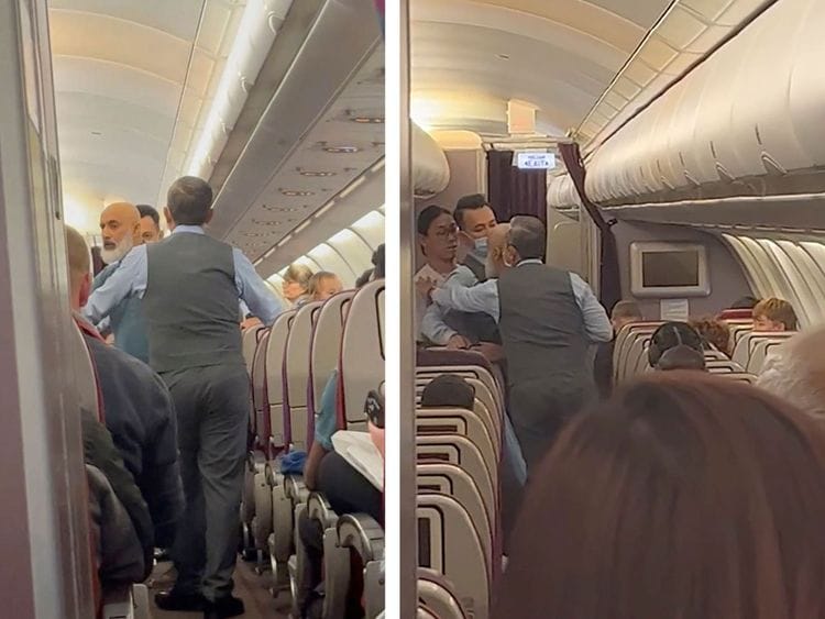 In this image taken from a video, a passenger standing in the aisle, second right, argues with crew members during a flight from Australia to Malaysia, Monday, Aug. 14, 2023