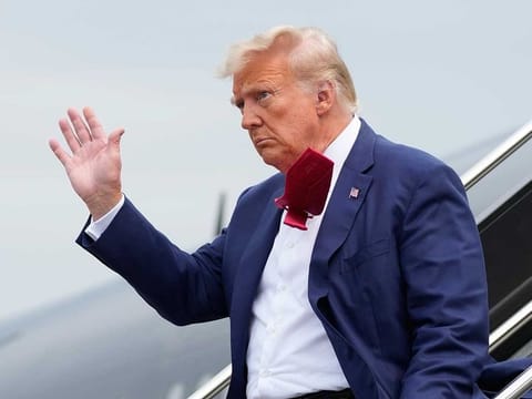 Former President Donald Trump waves as he steps off his plane at Ronald Reagan Washington National Airport, Aug. 3, 2023, in Arlington, Va. 