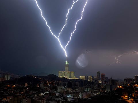 A picture taken on August 22, 2023 shows lightning over Mecca's clock tower in Saudi Arabia. Fierce storms closed schools on August 23 the kingdom's Mecca region, home to the holy Grand Mosque which was lashed by heavy rains and wind overnight, witnesses said.  