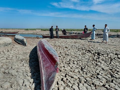 Boats can be seen on dried cracked earth in the Southern Marshes of Iraq. In Baghdad, the residents have never seen the water level in the Tigris and the Euphrates so depleted. People now cross the dry river bed of both rivers on foot