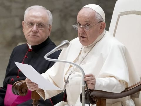 Pope Francis, right, flanked by Father Leonardo Sapienza, left, delivers his speech during his weekly general audience in the Pope Paul VI hall at the Vatican on August 30, 2023.  