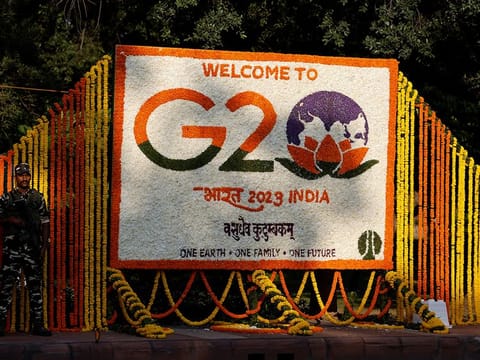A security force personnel stands guard next to a hoarding decorated with flowers on a pavement ahead of the G20 Summit in New Delhi, India, September 8, 2023. 