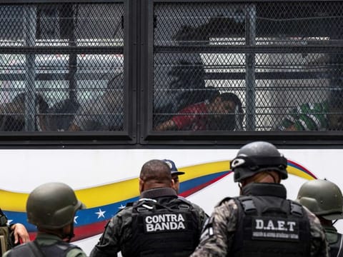 Members of the Bolivarian National Guard (GNB) stand guard as inmates aboard a bus are transferred outside the Tocoron prison in Tocoron, Aragua State, Venezuela, on September 20, 2023.  