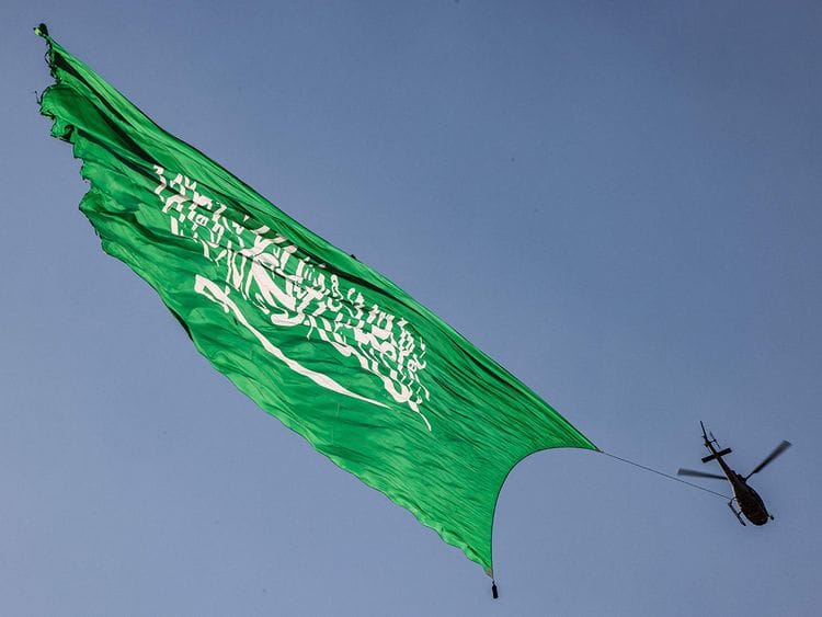 A helicopter flies over with a giant Saudi flag during an air show marking Saudi Arabia's 93rd National Day celebrations in Riyadh on September 23, 2023.  