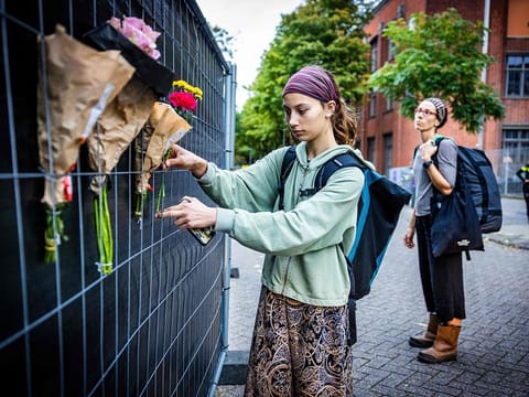 People attach flowers to a fence set outside the Erasmus university hospital in Rotterdam on September 29, 2023, a day after a woman, her 14-year-old daughter, and a teacher at the hospital were shot dead. 