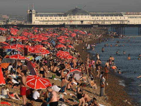 Looking towards the Palace Pier, beachgoers enjoy the sun and the sea on the beach at Brighton, on the south coast of England on September 7, 2023. Last month was the world's hottest September on record by an "extraordinary" margin, adding to record-breaking global temperatures during the Northern Hemisphere summer, the EU climate monitor said on Thursday.  