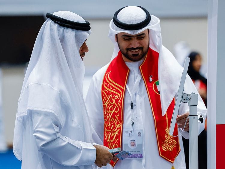 A voter (left) is guided to an electronic ID check before casting his vote at the Sharjah Chess Club polling centre