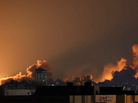 A plume of smoke rises above buildings in Gaza City during an Israeli air strike, on October 8, 2023. 
