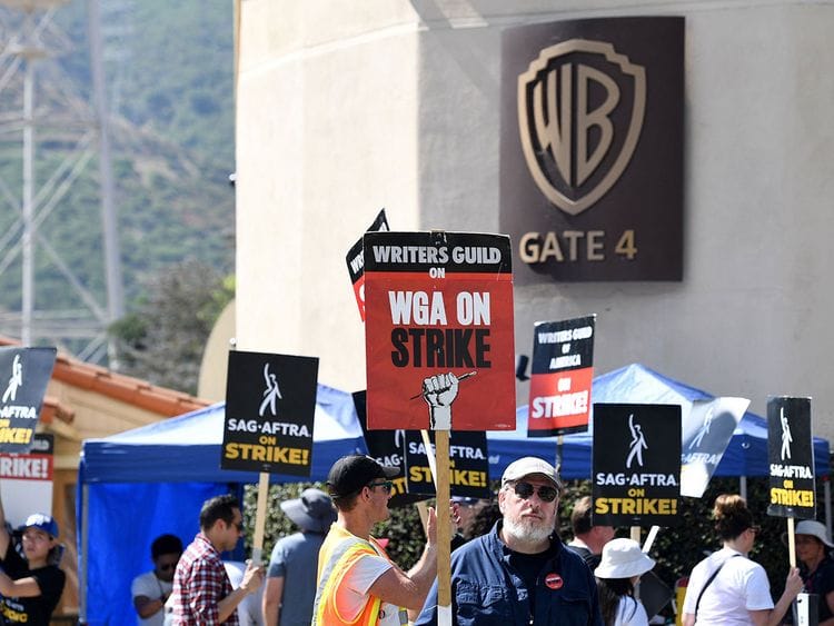 Members of the Writers Guild of America and the Screen Actors Guild walk a picket line outside of Warner Bros Studio in Burbank, California, on July 26, 2023. Hollywood writers overwhelmingly voted to approve a hard-fought new deal with studios, their union said October 9, 2023, officially ending one of the industry's longest ever strikes.