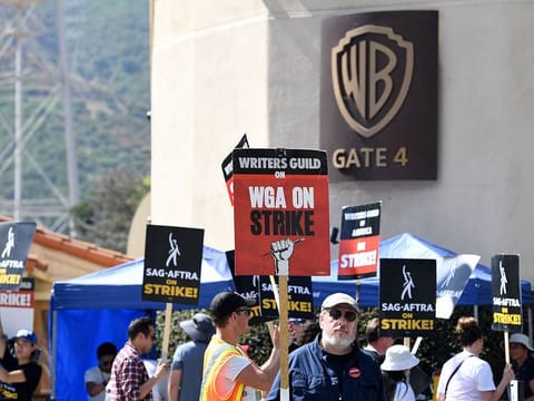 FILES: Members of the Writers Guild of America and the Screen Actors Guild walk a picket line outside of Warner Bros Studio in Burbank, California, on July 26, 2023. Hollywood writers overwhelmingly voted to approve a hard-fought new deal with studios, their union said October 9, 2023, officially ending one of the industry's longest ever strikes.