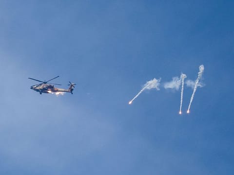 An Israeli Apache helicopter releases flares while patrolling over the Israel-Gaza border on October 11, 2023. Israel declared war on Hamas on October 8 following a shock land, air, and sea assault by the Gaza-based militant group.  