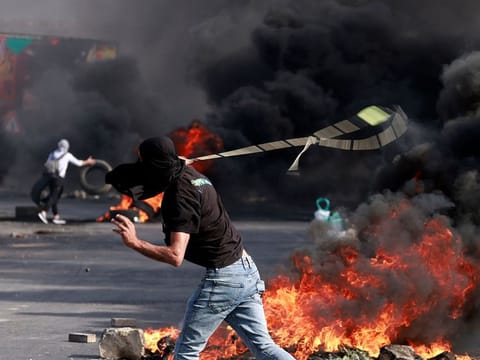 A Palestinian uses a slingshot during clashes with Israeli soldiers at the north entarnce of the city of Ramallah, in West Bank on October 13, 2023.  