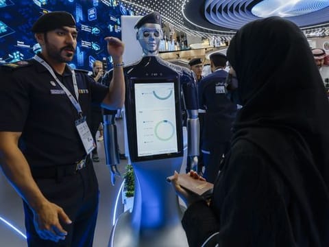 An official (left) provides information about the robot (centre) displayed at the Abu Dhabi Airport stand during Gitex Global 2023 at Dubai World Trade Centre