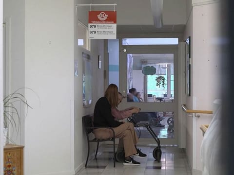 Caroline Wahlberg (L), manager of the Tallhojden nursing home in Sodertalje, sits with an elder man on the bench of a fake bus stop installed in a corridor of the facility dedicated to patients with dementia.