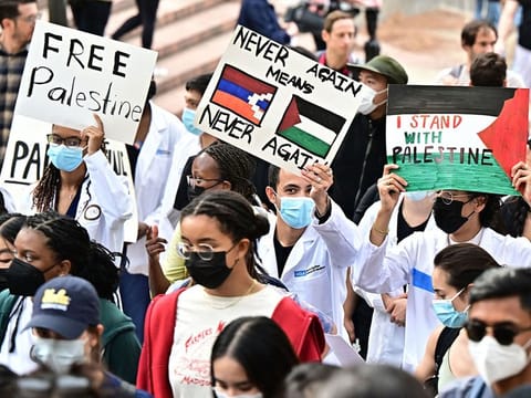A protester holds a placard showing a Palestinian flag as students participate in a "Walkout to fight Genocide and Free Palestine" at Bruin Plaza at UCLA (University of California, Los Angeles) in Los Angeles on October 25, 2023