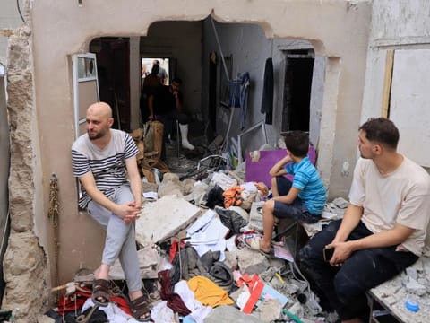 People sit amid the rubble of a building in the aftermath of an Israeli strike on Khan Younis in the southern Gaza Strip on October 29, 2023.  