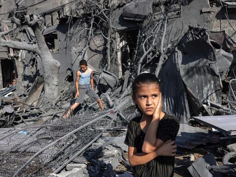 A girl looks on as she stands by the rubble outside a building that was hit by Israeli bombardment in Rafah in the southern Gaza Strip 
