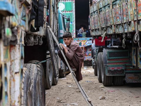 An Afghan refugee boy climbs a truck as he prepares to depart for Afghanistan, at a holding centre in Landi Kotal on November 1, 2023.