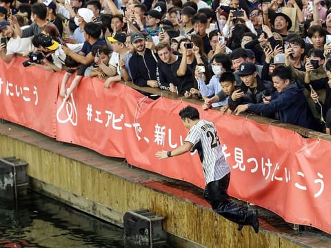 A Hanshin Tigers supporter jumps into the Dotonbori River in downtown Osaka following the Tigers victory in the Nippon Series baseball championship for the first time in 38 years, after beating the Orix Buffaloes 7-1 in Game 7 of the best-of-seven series in Osaka.