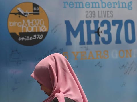 A girl stands in front of a condolence message board during a Day of Remembrance for MH370 event in Kuala Lumpur, Malaysia. | File photo