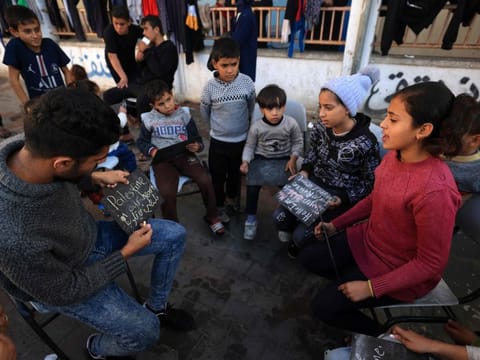 Tarek Al Anabi, a 25-year-old Palestinian man, gathers displaced children at the Taha Hussein school which is used as a temporary shelter, to give them English lessons, in Rafah in the southern Gaza Strip on November 29, 2023, amid a cease fire following weeks of battles between Israel and Palestinian Hamas militants.  
