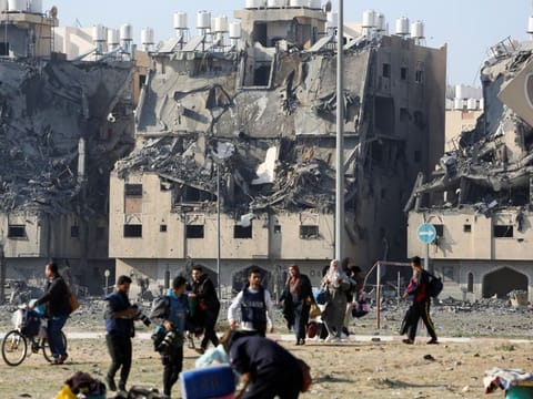 Buildings lie in ruin as Palestinians carry their belongings following Israeli strikes on residential buildings at the Qatari-funded Hamad City, amid the ongoing conflict between Israel and the Palestinian Islamist group Hamas, in Khan Younis in the southern Gaza Strip on December 2, 2023.  