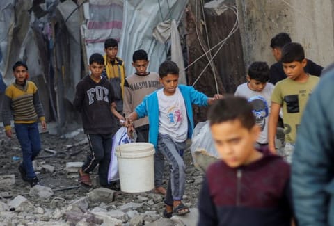 Palestinian children carry items as they walk at the site of Israeli strikes, amid the ongoing conflict between Israel and the Palestinian Islamist group Hamas, in Khan Younis in the southern Gaza Strip, December 6, 2023. REUTERS/Ahmed Zakot