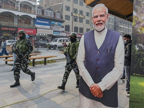 Indian paramilitary troopers patrol past a cut-out of India's Prime Minister Narendra Modi in Srinagar on December 11, 2023.
