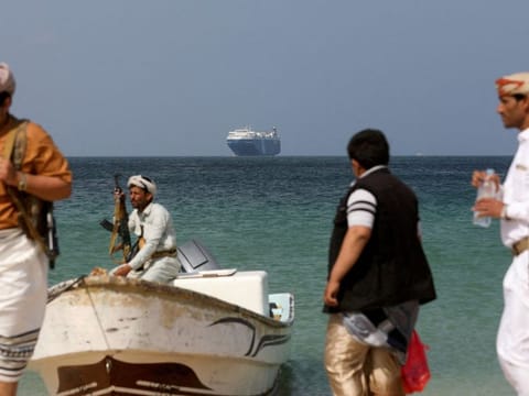 Armed Houthis  stand on the beach as the Galaxy Leader commercial ship, seized by the militants last month, is anchored off the coast of Al Salif, Yemen.