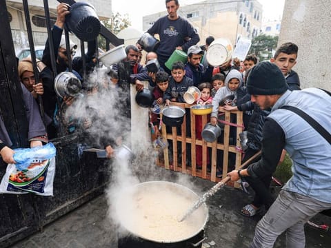 Palestinians wait to collect food at a donation point in a refugee camp in Rafah in the southern Gaza Strip on December 23, 2023, amid continuing battles between Israel and Hamas. 