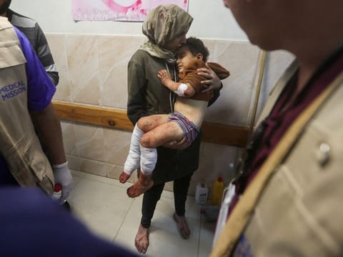 A Palestinian woman holds a child wounded in an Israeli strike, at a hospital in Khan Younis in the southern Gaza Strip on December 28, 2023.  