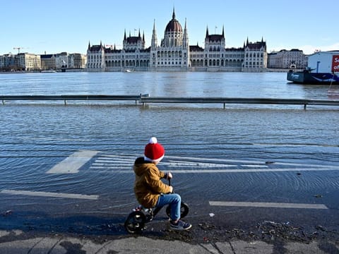 A child rides his bike on a quay flooded by the Danube River in Budapest on December 27, 2023.  