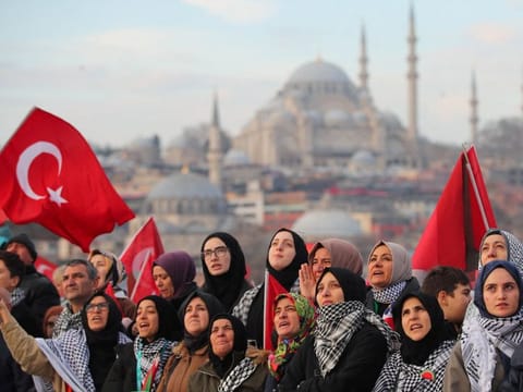 People gather over the Galata Bridge in solidarity with Palestinians, amid the ongoing conflict between Israel and the Palestinian Islamist group Hamas, following the first morning prayer of the New Year in Istanbul, on January 1, 2024.  The Gaza war ended a gradual thawing in Turkish-Israeli relations that culminated with the reappointment of ambassadors in 2022.