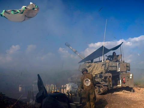 An Israeli soldier wearing a patch on the back of his flack jacket showing Lebanon's Hezbollah leader Hassan Nasrallah as a target, stands in front of a tank in Upper Galilee in northern Israel, as an artillery unit shells southern Lebanon on January 4, 2024. Nasrallah warned Israel against all-out conflict, after Israeli army chief Herzi Halevi, in a visit to the Lebanese border, said troops were "in very high readiness".  